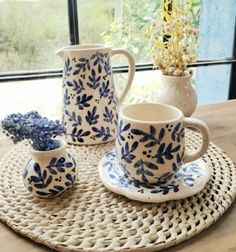 blue and white pottery is sitting on a wicker place mat next to a window