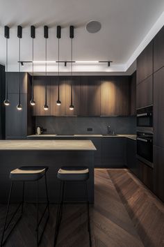 a modern kitchen with dark wood cabinets and stools