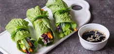 lettuce wrapped in leafy greens next to a small cup of dipping sauce