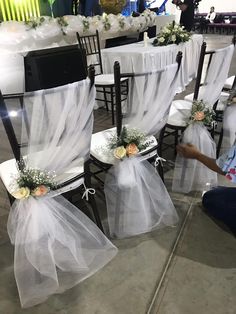 the chairs are decorated with white tulle and flowers