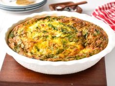 a casserole dish with spinach and cheese in it on a wooden cutting board