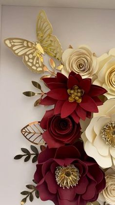 paper flowers are arranged on the wall in an arrangement with gold leaves and butterflies,