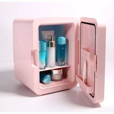 a pink mini refrigerator with its door open and various items in it, including toothbrushes