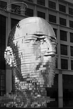 black and white photograph of a giant head in front of a building