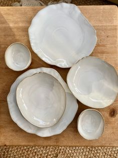 four white plates and two bowls on a cutting board