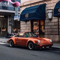 an orange car is parked on the side of the street