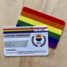 two rainbow colored credit cards sitting on top of a wooden table next to each other