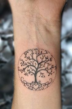 a tree tattoo on the wrist with leaves and branches around it, in black ink