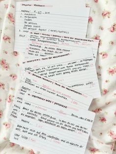 three pieces of paper sitting on top of a bed covered in pink and white flowers