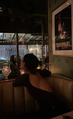 a woman sitting at a table in front of a window with wine glasses on it