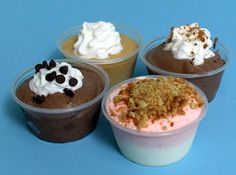 four different desserts in plastic cups on a blue surface