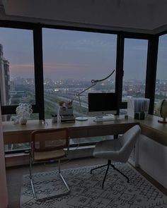 a desk with a computer on top of it in front of a large window overlooking the city