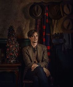 a man sitting in a chair next to a christmas tree