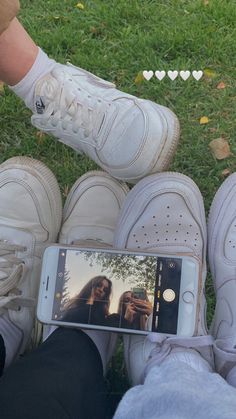 someone taking a selfie with their cell phone in front of two pairs of shoes