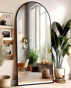 an arched mirror in the corner of a room with potted plants and pictures on the wall