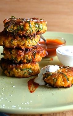 three crab cakes on a green plate with sauce