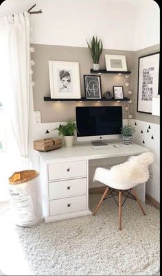 a white desk topped with a computer monitor next to a wooden cabinet filled with drawers