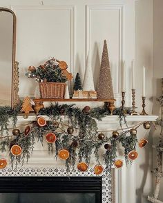 a fireplace mantel with candles and ornaments on it, including pine cones, oranges, fir trees, and other holiday decorations