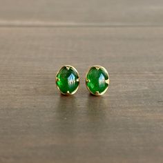 Vibrant, incredibly rare green color springs from within these cabochon tsavorite garnets, each poised in its "claw" setting. 18k yellow gold Garnet (sourced in Africa), 5/16" x 3/8" (7mm x 9mm) Each earring weighs 1.7g Green Gemstone Cabochons For Formal Use, Yellow Gold Tsavorite Gemstone Earrings, Elegant Green Gemstone Cabochons, Gold Tsavorite Gemstone Earrings, Emerald Cabochon Earrings As A Gift, Emerald Cabochon Earrings For Gift, Tsavorite Gemstone Earrings For May Birthstone, 14k Gold Green Cabochon Jewelry, Tsavorite Yellow Gold Earrings For Gift