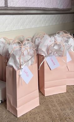 small pink bags with tags on them are sitting on the floor in front of a bed