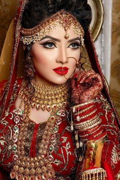 a woman in red and gold wedding outfit with jewelry on her head, wearing an elaborate veil