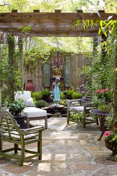 an outdoor patio with chairs, tables and potted plants on the ground in front of a pergolated area