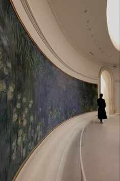 a person standing in front of a large painting on the side of a wall with water lillies