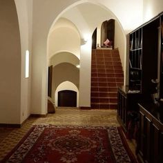 a hallway with an arched doorway and stairs leading up to the second floor in a home