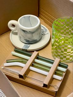 a cup, saucer, and pencils are sitting on a table next to each other