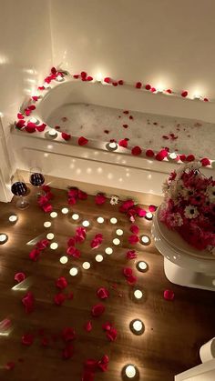 a bathtub with candles and flowers on the floor next to it is lit up