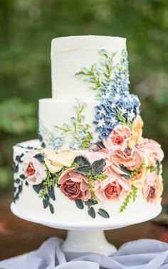 a wedding cake decorated with flowers and greenery