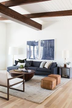 a living room with white walls and wood beams on the ceiling is furnished with modern furniture