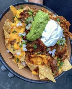 a plate filled with nachos topped with sour cream and guacamole