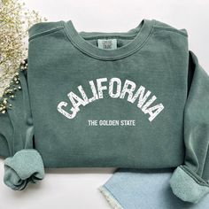 California Golden State Unisex Sweatshirt Californian Gift California Souvenir Luxurious comfort and style are what this unisex, garment-dyed sweatshirt is all about. It's made with 80% ring-spun cotton and 20% polyester and the fabric is 3-end garment-dyed, ring-spun, color-blast fleece with a 100% cotton face. Each sweatshirt comes with a relaxed fit, a rolled-forward shoulder, and a back neck patch.  .: 80% ring-spun cotton, 20% polyester .: Medium-heavy fabric (9.5 oz /yd² (322.1 g/m .: Relaxed fit .: Sewn in twill label .: OEKO-TEX certified low-impact dyes Collegiate Crew Sweatshirt With Screen Print, Collegiate Style Crew Sweatshirt With Screen Print, Cotton Fan Apparel Sweatshirt For Campus, Cotton Sweatshirt For Campus Fan Apparel, Collegiate Cotton Sweatshirt With Screen Print, Relaxed Fit Lettering Tops For Campus, Relaxed Fit Cotton College Style Sweatshirt, Varsity Cotton Sweatshirt With Screen Print, Collegiate Sweatshirt With Screen Print, Relaxed Fit