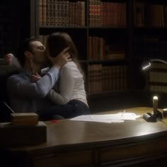 a man and woman sitting at a desk kissing