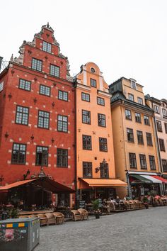 several buildings with tables and umbrellas in front of them