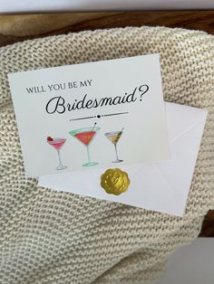 a card that says will you be my bridesmaid? with two martini glasses