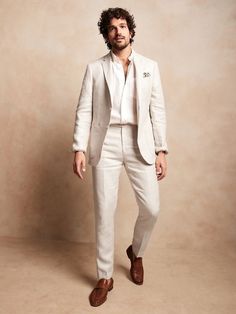 a man in a white suit and brown shoes