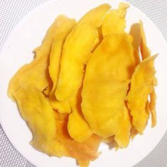 a white plate topped with cut up pieces of yellow fruit on top of a table