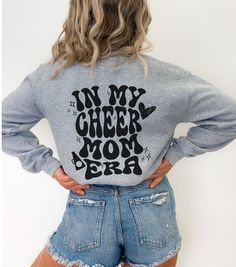 ** Custom Cheer Mom Sweatshirt, Retro Cheer Era Sweatshirt, Gift for Mom, Cheerleading Sweatshirt Gildan 18000, Cheer Mom Gift Personalized** This sweatshirt will really show your cheerleader how much you support them. This personalized Cheer Mom sweatshirt is a nice medium weight material, with the softest and coziest feeling inside. The design is printed directly into the fabric, so you will never have to worry about peeling or cracking! This style does give your sweatshirt a more distressed/w Cheerleading Tops For Fall, Relaxed Fit Long Sleeve Tops For School Spirit, Long Sleeve Tops With Relaxed Fit For School Spirit, Fall Cheerleading Top With Letter Print, Casual Tops For Cheerleading In Fall, School Spirit Graphic Print Top For Winter, College Heather Grey Tops With Letter Print, Heather Grey Letter Print Top For College, Long Sleeve Letter Print Sweater For School Spirit