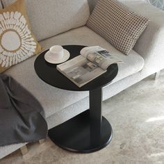 a coffee table with a magazine on it in front of a gray couch and pillows