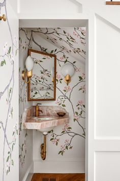 a bathroom with floral wallpaper and gold faucet in the corner, along with a marble sink