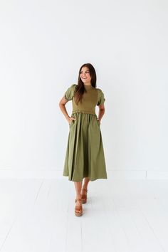 Features Mock neck Short puff sleeves with elastic Ribbed bodice Elastic waist Olive color Pockets 60% Cotton, 40% Polyester; Contrast: 52% Viscose, 26% Polyester, 22% Nylon Size + Fit Small 0-4, Medium 4-8, Large 8-12, X-Large 14-16, 1X 16-18, 2X 20-22, 3X 24-26 Kristin is 5'4", a size 1 and is wearing a Small Jaycie is 5'6" a size 18 and is wearing a 2X Runs true to size. Measurements taken while laying flat and then doubled. They do no account for stretch. Size Bra Band Length Small 34" 46" M Spring Dresses With Elastic Shoulders And Stretch, Spring Midi Dress With Pleated Waist And Stretch, Spring Dresses With Stretch Elastic Shoulders, Spring Stretch Midi Dress With Pleated Waist, Fitted Midi Dress With Elastic Waistband For Daywear, Fitted Midi Dress With Elastic Waistband, Fitted Solid Color Dress With Elastic Waistband, Modest Fitted Puff Sleeve Dress With Short Sleeves, Fitted Midi Dress With Gathered Waist And Puff Sleeves