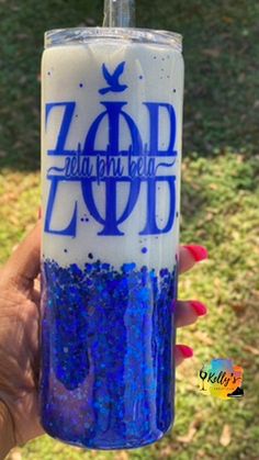 a person holding up a blue and white cup with glitter on the bottom that says zoop