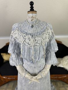 Two-piece summer dress from the Edwardian period, ca. 1903. The antique dress is a two-piece dress. It is made from a thin, printed cotton fabric. Pattern: light blue flowers and leaves on a light background. High neckline made of bobbin lace or rather crocheted lace. This lace is continued as decoration in the chest area. Additional hanging tassels made from the yarn are attached here. The sleeves are also made from the same crochet yarn from the elbow upwards. Hanging chest, which is decisive Victorian Era Fashion Woman, Victorian Dress Blue, 1880s Dress, Hanging Tassels, Victorian Era Fashion, Tea Gown, Edwardian Dress, 20th Century Fashion, Light Blue Flowers