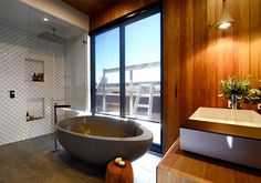 a bath tub sitting next to a large window in a bathroom with wood paneling