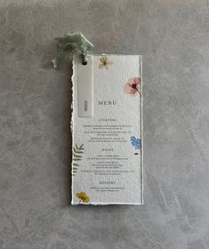 a menu card with flowers on it sitting on top of a gray tablecloth covered floor