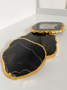 two black and gold trays sitting on top of a white table