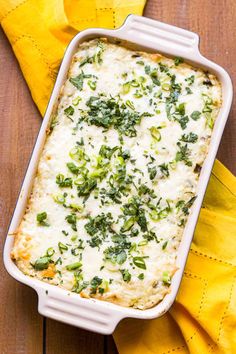 a casserole dish with cheese and herbs in it sitting on a yellow napkin