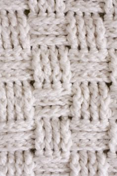 close up view of the crochet stitch pattern on a white knitted blanket